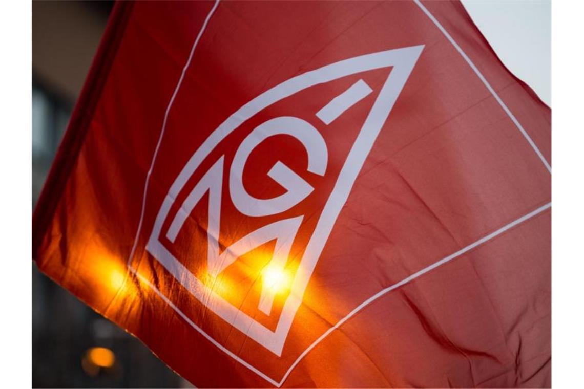 Eine Fahne mit dem Logo der IG-Metall wird geschwenkt. Foto: Lino Mirgeler/Archiv