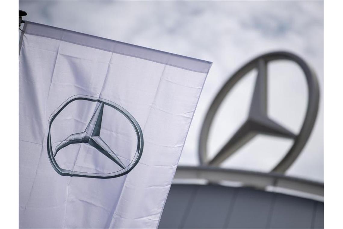 Daimler bereitet Konzern-Aufspaltung auch in Chefetage vor Eine Fahne mit dem Mercedes-Stern weht vor einem Showroom der Firma. Foto: Sebastian Gollnow/dpa/Archivbild