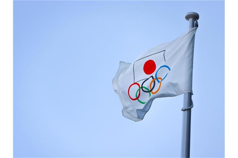 Eine Fahne mit der Flagge Japans und den Olympischen Ringen weht auf einem Mast in Tokio. Foto: Stanislav Kogiku/SOPA Images via ZUMA Wire/dpa/Archivbild
