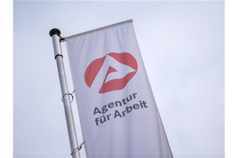Eine Fahne weht vor der Agentur für Arbeit. Foto: Daniel Bockwoldt/dpa/Archiv