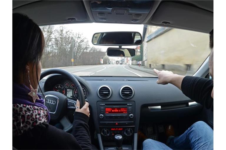 Eine Fahrschülerin sitzt in einem Fahrschulauto neben ihrem Fahrlehrer. Foto: Armin Weigel/dpa