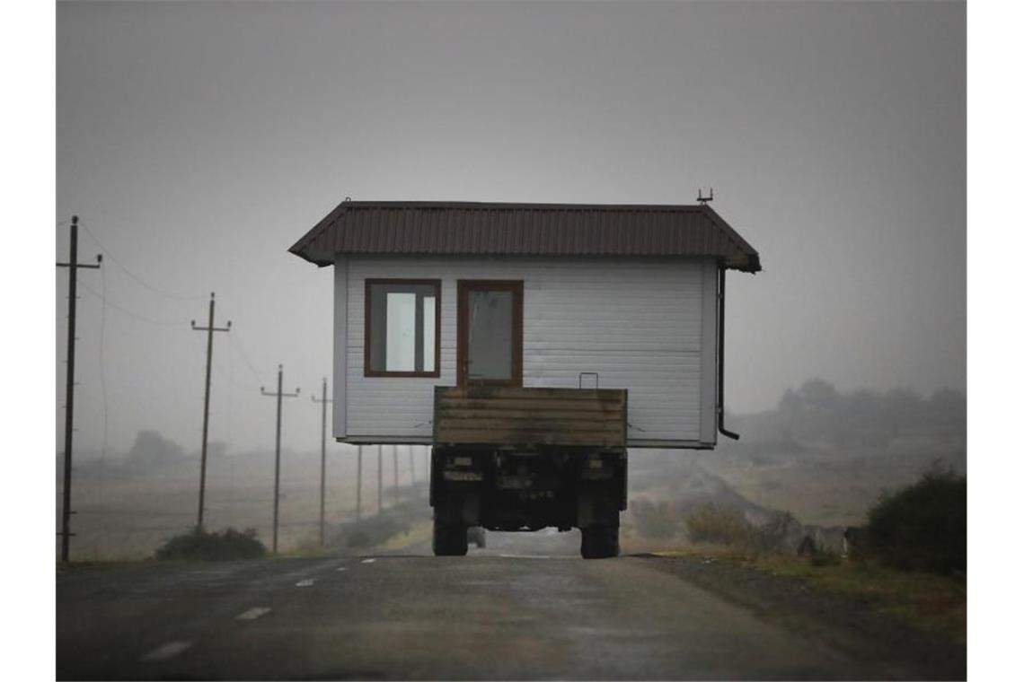 Eine Familie befördert ihr kleines Haus auf einem Lastwagen, als sie ihr Heimatdorf in der Region Berg-Karabach verlassen. Foto: Sergei Grits/AP/dpa