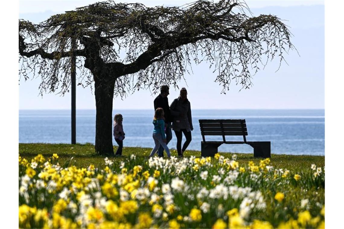Regierung ruft zu Einhaltung der Kontaktverbote auf Eine Familie läuft in Langenargen an der Promenade am Bodensee entlang. Foto: Felix Kästle/dpa