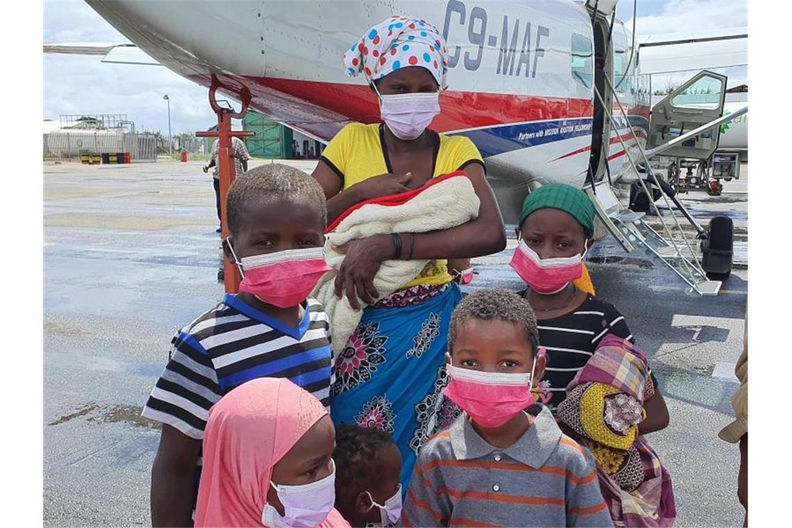 Eine Familie steht auf dem Rollfeld des Flughafens der Provinzhauptstadt Pemba, nachdem sie evakuiert wurden. In der Provinz Cabo Delgado verüben islamistische Rebellen seit 2017 immer wieder brutale Attacken. Nach Angaben des Welternährungsprogramms (WFP) sind in der Region fast eine Million Menschen infolge von Terror und Gewalt vom Hunger bedroht. Foto: Dave Lepoidevin/Ambassador Aviation/AP/dpa