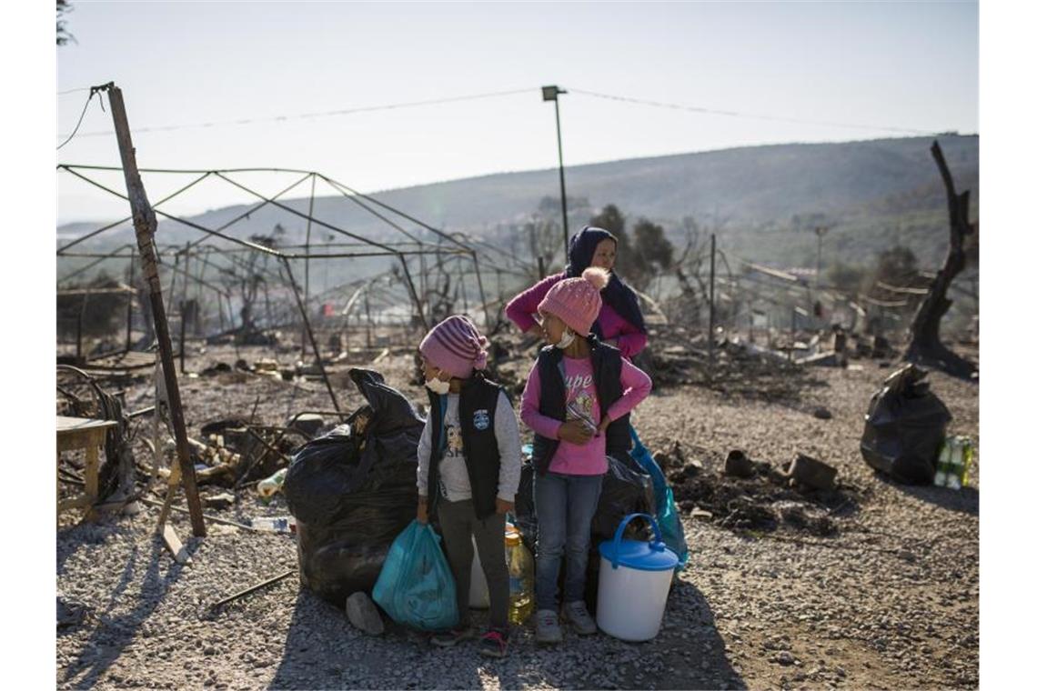 Eine Familie steht innerhalb des ausgebrannten Flüchtlingslagers Moria. Mehrere Brände haben das Lager fast vollständig zerstört. Foto: Socrates Baltagiannis/dpa