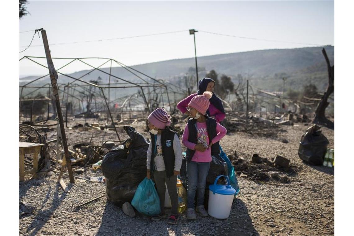 Eine Familie steht vor dem abgebrannten Flüchtlingslager Moria. Foto: Socrates Baltagiannis/dpa/Archivbild