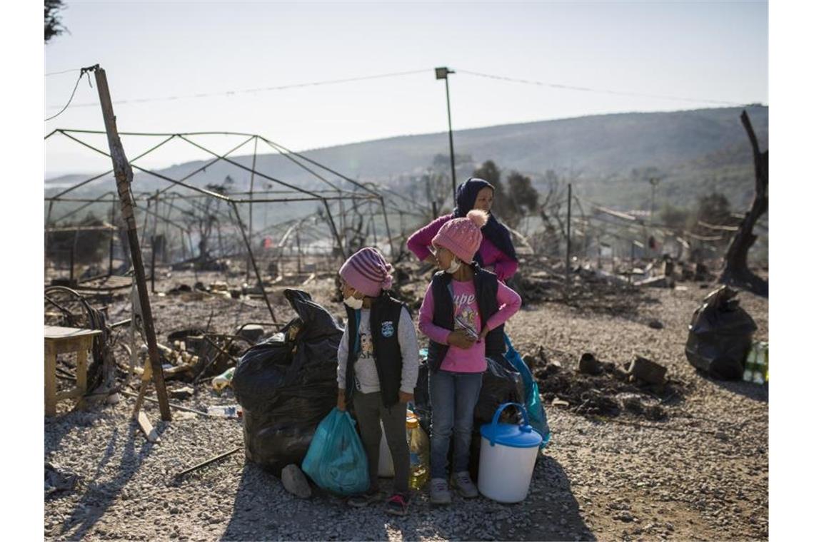 Kretschmann lobt Vorschlag: Aufnahme von Flüchtlingsfamilien Eine Familie steht vor dem abgebrannten Flüchtlingslager Moria. Foto: Socrates Baltagiannis/dpa/Archivbild