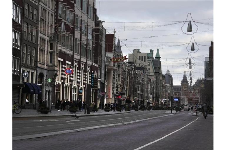 Eine fast menschenleere Straße in Amsterdam. In den Niederlanden gilt bis mindestens 14. Januar ein harter Lockdown. Foto: Peter Dejong/AP/dpa