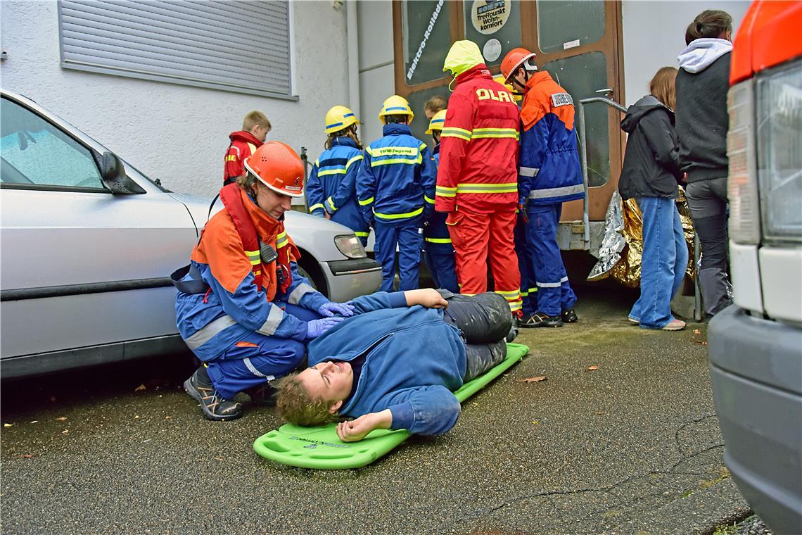 Eine Feuerwehrfrau betreut einen Verletzten und redet ihm gut zu. Feuerwehr-Juge...