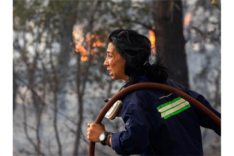 Eine Feuerwehrfrau versucht ein Feuer etwa 30 Kilometer von der griechischen Hauptstadt Athen zu löschen. Vielerorts sind die Brände außer Kontrolle geraten, es kommt zunehmend internationale Hilfe an. Foto: Marios Lolos/XinHua/dpa