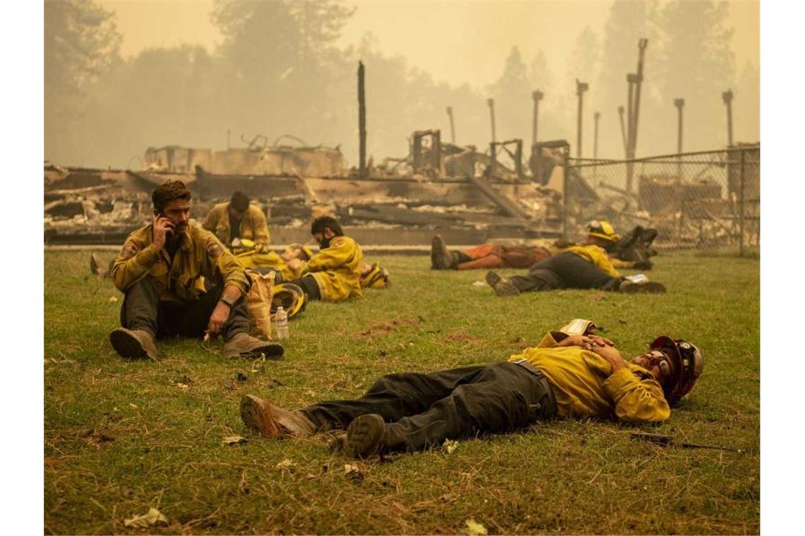 Eine Feuerwehrmannschaft macht eine Pause neben einer Schule in Berry Creek in Nordkalifornien, die durch ein Feuer zerstört wurde. Verheerende Waldbrände wüten weiter entlang weiten Teilen der US-Westküste. Foto: Jason Pierce/Sacramento Bee via ZUMA Wire/dpa