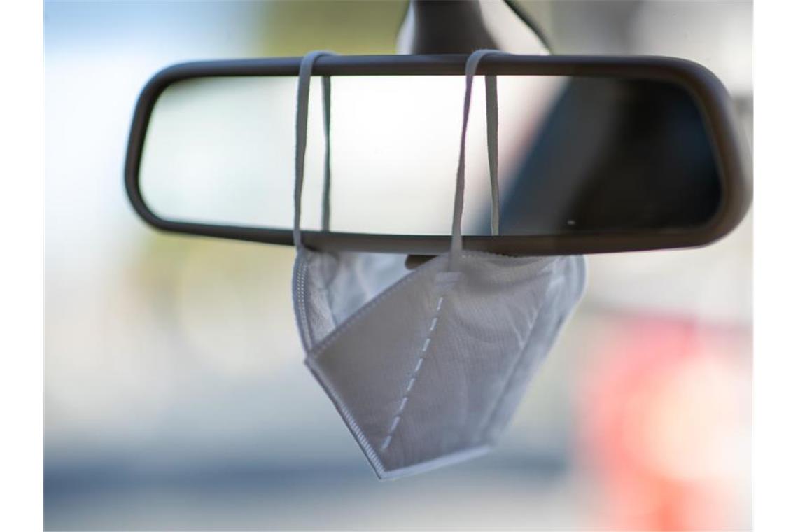 Pflicht zur Mitnahme von Schutzmasken im Auto geplant Eine FFP2-Maske hängt am Rückspiegel eines Autos (Symbolbild). Foto: Daniel Karmann/dpa