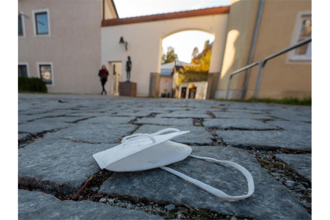 Eine FFP2-Maske liegt auf einem Weg in der Innenstadt von Pfarrkirchen in Bayern. Foto: Armin Weigel/dpa