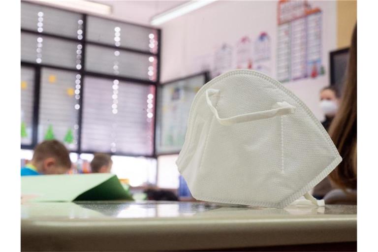 Eine FFP2-Maske liegt in einer ersten Klasse an einer Grundschule. Foto: Sebastian Gollnow/dpa