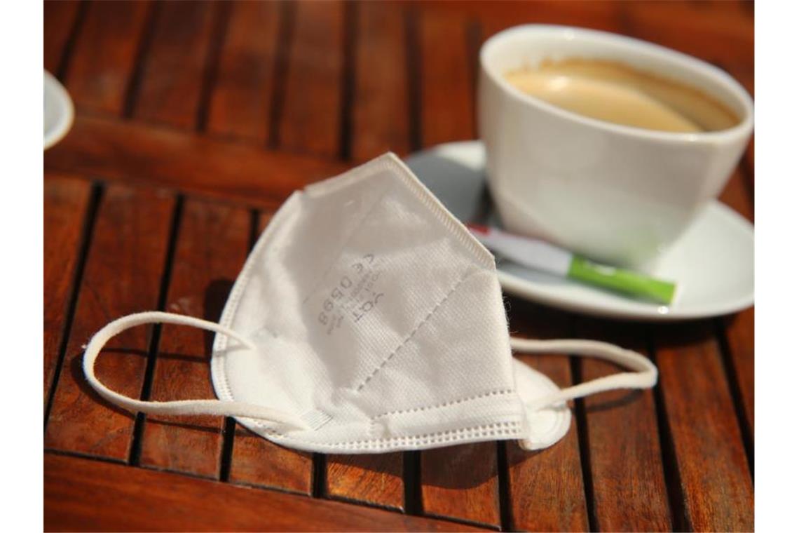 WHO vermeldet weltweiten Rückgang der Zahl von Corona-Fällen Eine FFP2-Maske liegt neben einer Tasse Kaffee auf einem Tisch. (Archivbild). Foto: Matthias Bein/dpa-Zentralbild/dpa