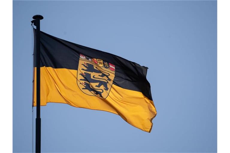 Eine Flagge des Landes Baden-Württemberg weht vor blauem Himmel im Wind. Foto: Marijan Murat/dpa/Archivbild