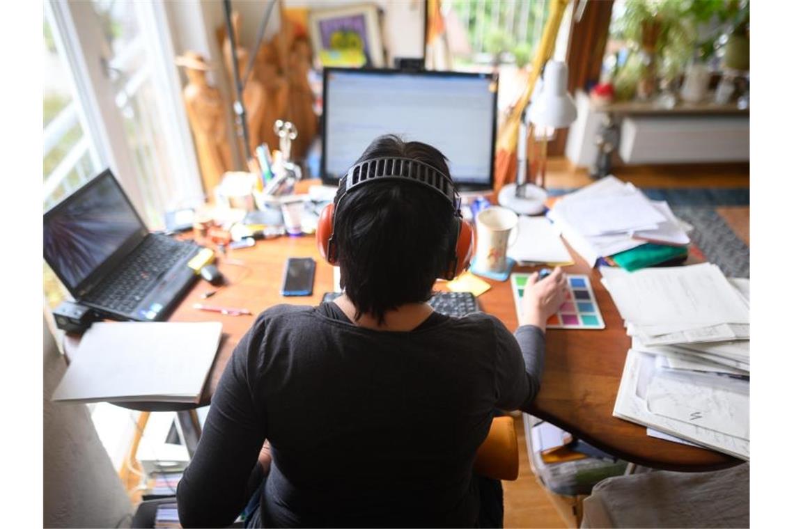 Eine Frau arbeitet mit Hörschutz im Homeoffice. Foto: Sebastian Gollnow/dpa/Archivbild