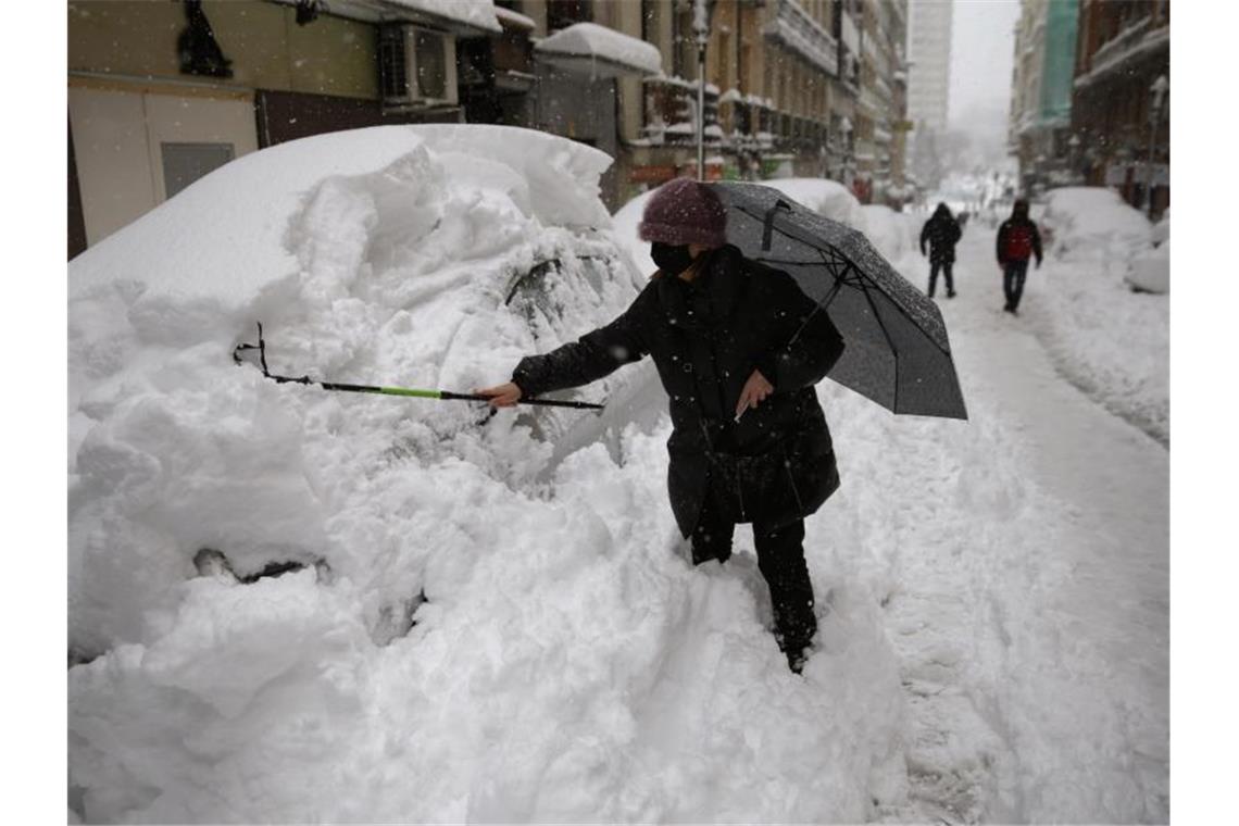 Eine Frau befreit ihr Auto in Madrid vom Schnee. Foto: Andrea Comas/AP/dpa