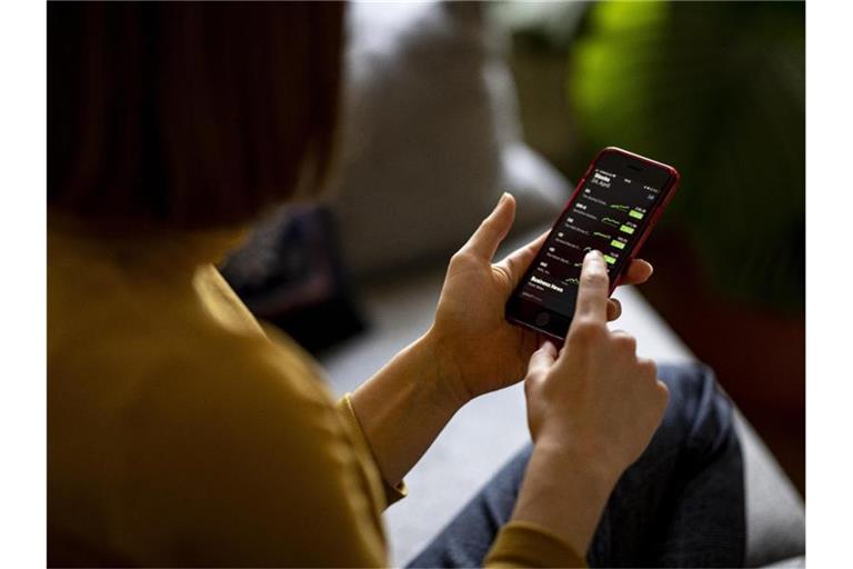 Eine Frau beobachtet mit ihrem iPhone die Aktienkurse in der App Stocks. Foto: Fabian Sommer/dpa