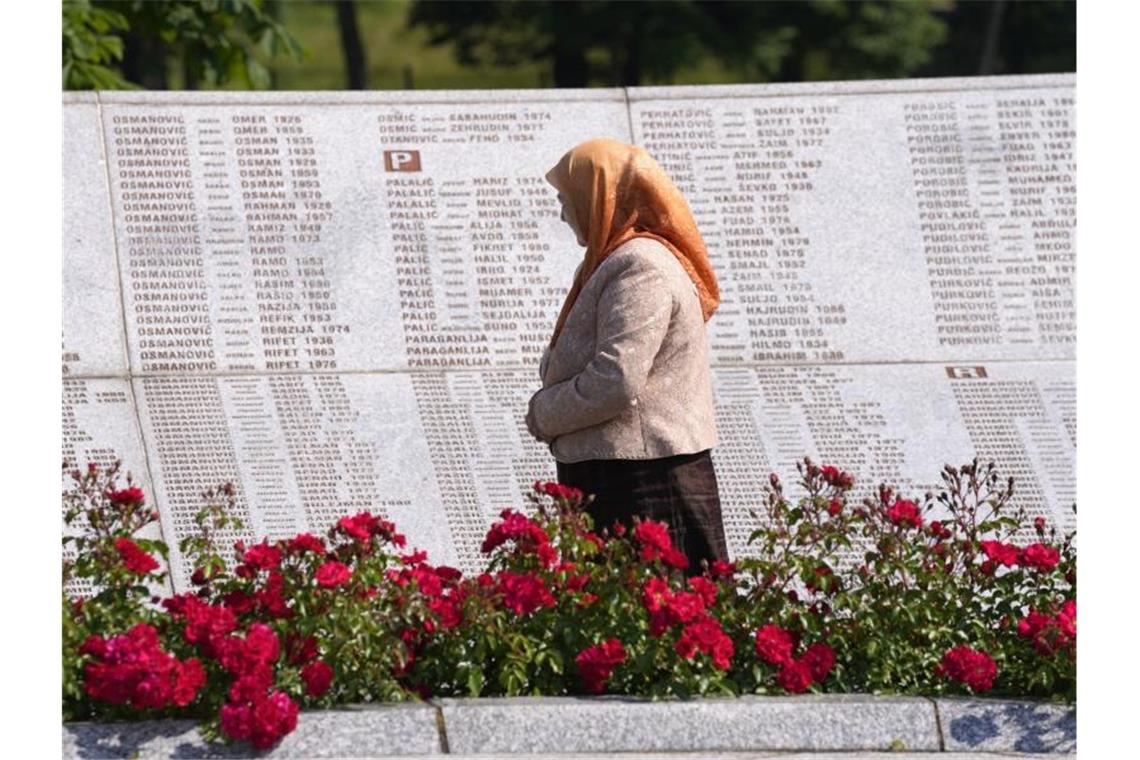 Eine Frau betrachtet auf dem Gedenkfriedhof für die Opfer des Massakers von Srebenica Namen von Getöteten. Etwa 8000 muslimische Männer und Jungen wurden im Juli 1995 von Mladics Männern ermordet. Foto: Darko Bandic/AP/dpa