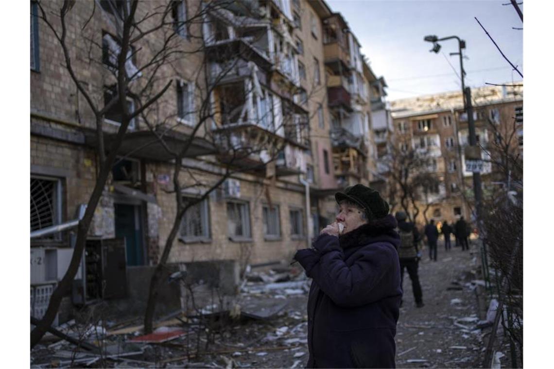 Russland wirft Kiew Angriffspläne auf Diplomaten vor Eine Frau betrachtet ein durch eine Bombe beschädigtes Wohnhaus in Kiew. Foto: Rodrigo Abd/AP/dpa