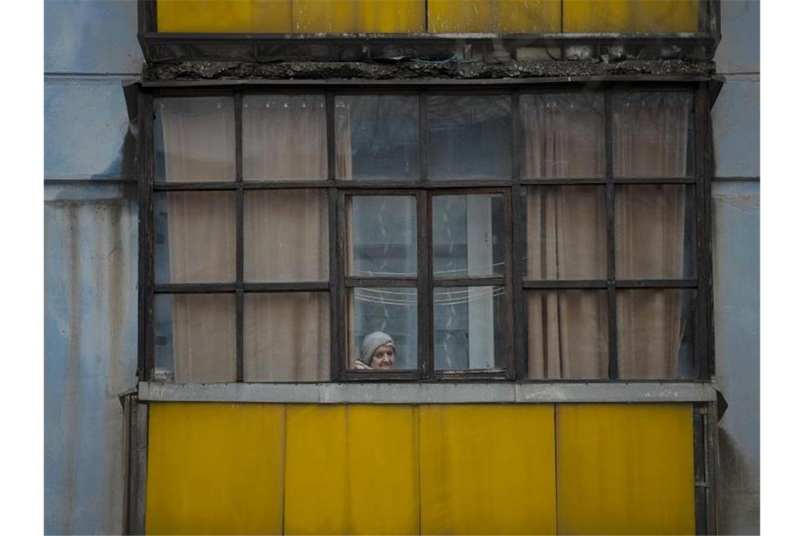 Nato befürchtet „vollständigen Angriff“ auf Ukraine Eine Frau blickt aus dem Fenster eines Hauses in Sjewjerodonezk im Osten der Ukraine. Foto: Vadim Ghirda/AP/dpa