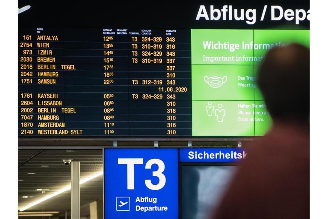 Eine Frau blickt im Terminal 3 auf die Abflugstafel des Stuttgarter Flughafens. Foto: Christoph Schmidt/dpa