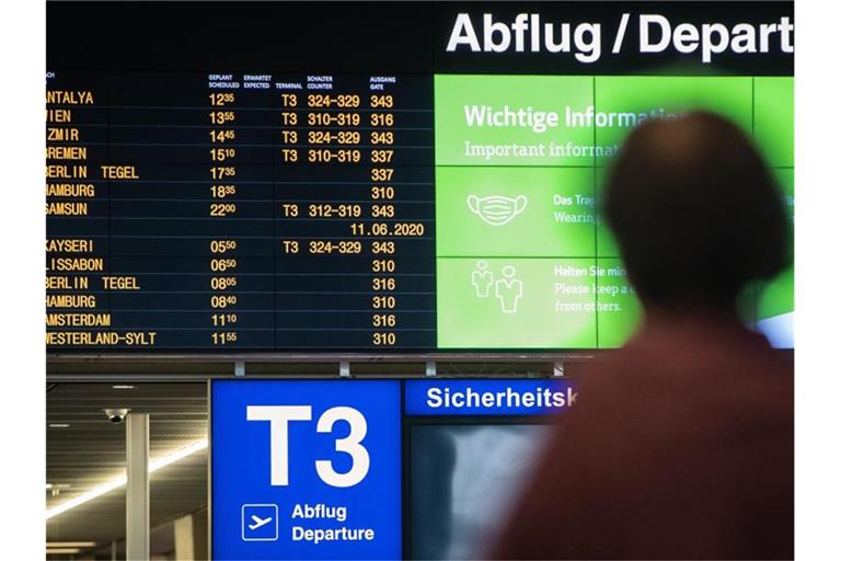 Eine Frau blickt im Terminal 3 auf die Abflugstafel des Stuttgarter Flughafens. Foto: Christoph Schmidt/dpa/Archivbild
