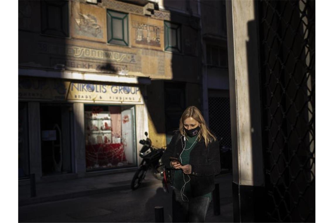 Eine Frau, die eine schützende Gesichtsmaske trägt, geht im Zentrum von Athen. Foto: Petros Giannakouris/AP/dpa