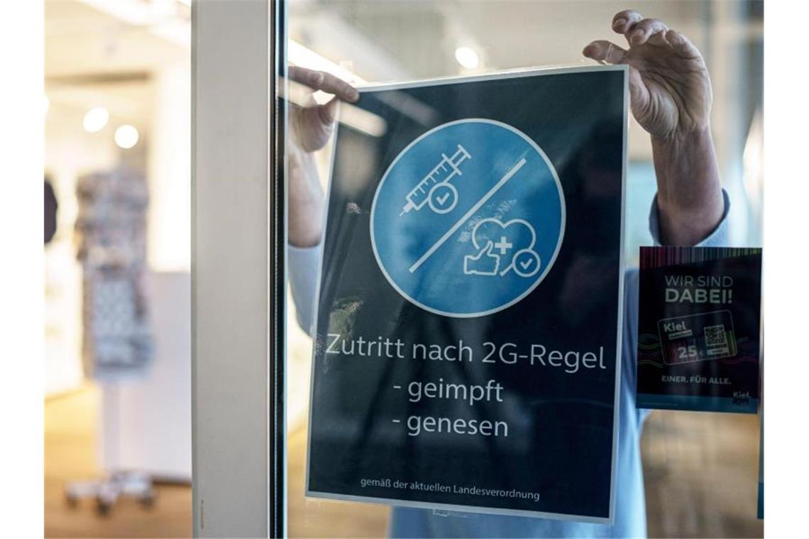 Corona-Pandemie: Kein Aufatmen in den Innenstädten Eine Frau entfernt von der Eingangstür des Welcome Center Kieler Förde das 2G Hinweisschild. Foto: Axel Heimken/dpa