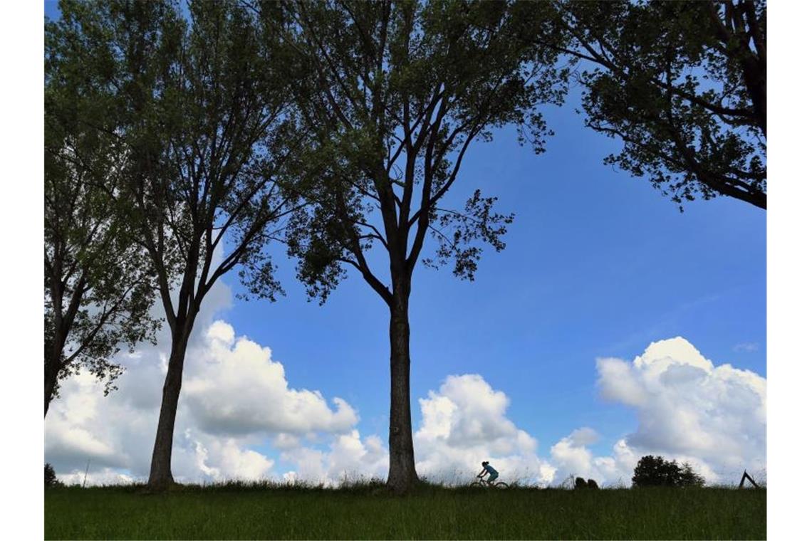 Wechselhafter Samstag in Baden-Württemberg Eine Frau fährt auf ihrem Fahrrad vor dem teilweise mit Wolken überzogenen Himmel. Foto: Karl-Josef Hildenbrand/dpa/Symbolbild