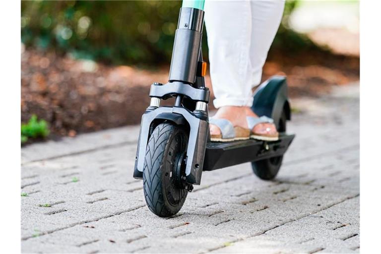 Eine Frau fährt einen E-Scooter eines Elektro-Tretroller-Sharing-Anbieters auf einem Fuß- und Radweg. Foto: Uwe Anspach/Archivbild