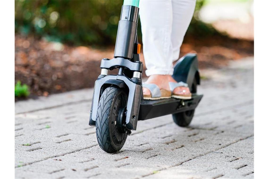 Eine Frau fährt einen E-Scooter eines Sharing-Anbieters auf einem Fuß- und Radweg in Heidelberg. Foto: Uwe Anspach/Archivbild