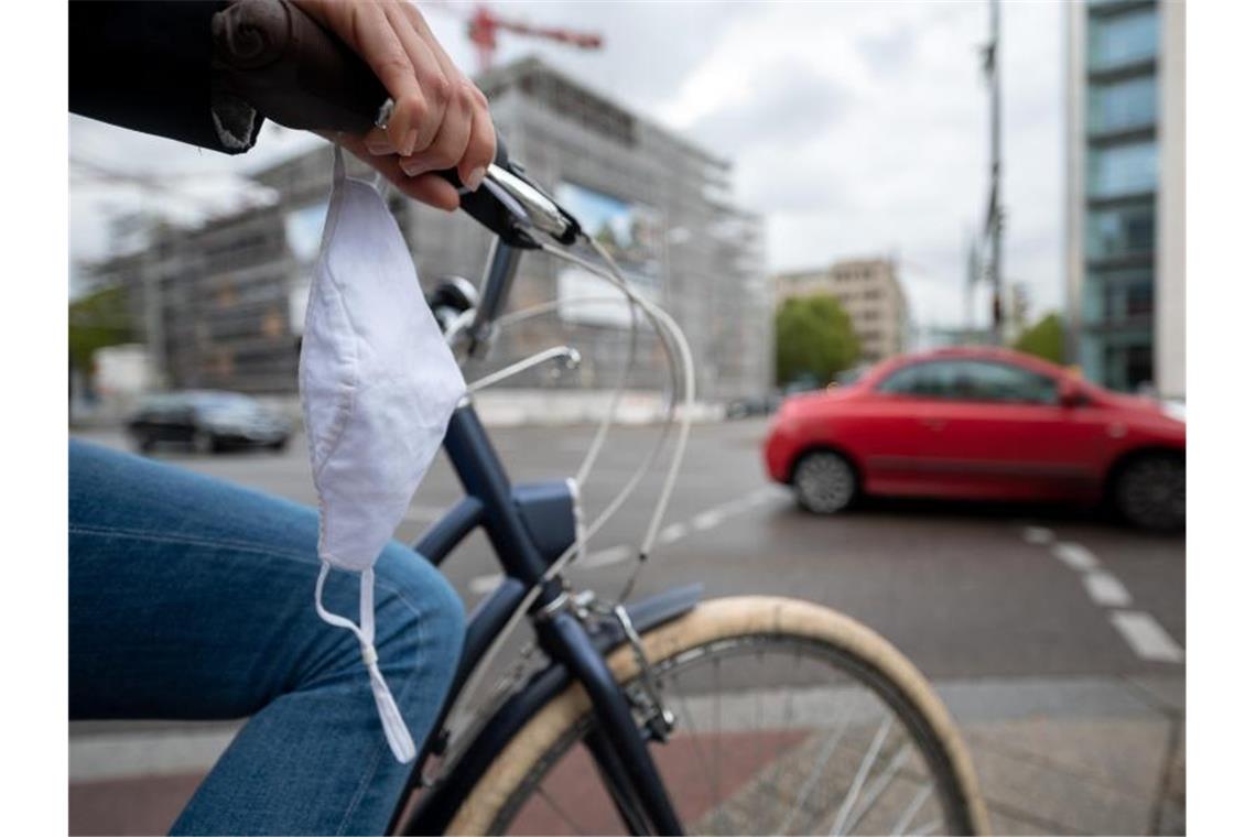 Eine Frau fährt mit Fahrrad und Mundschutz durch Stuttgart. Foto: Sebastian Gollnow/dpa