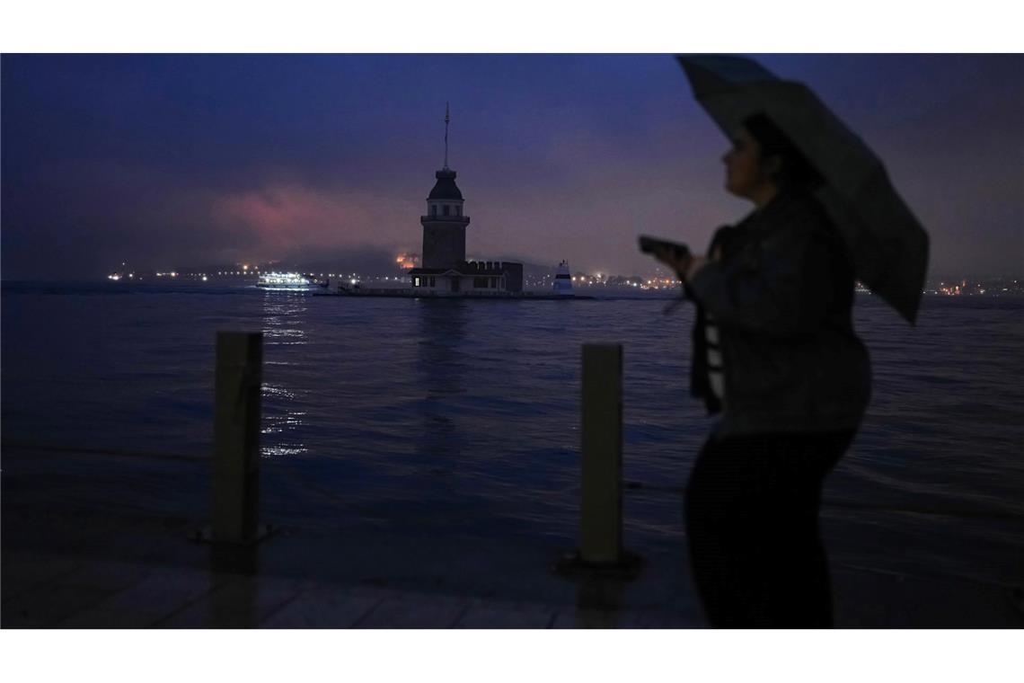 Eine Frau geht an einem regnerischen Tag in Istanbul am Jungfernturm am Bosporus vorbei.