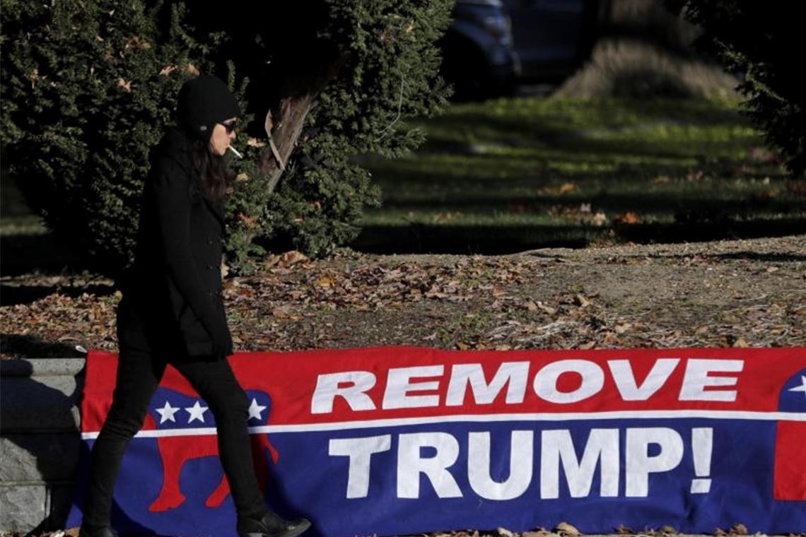 Eine Frau geht an einem Schild mit dem Schriftzug „Remove Trump“ vorbei. Foto: Julio Cortez/AP/dpa