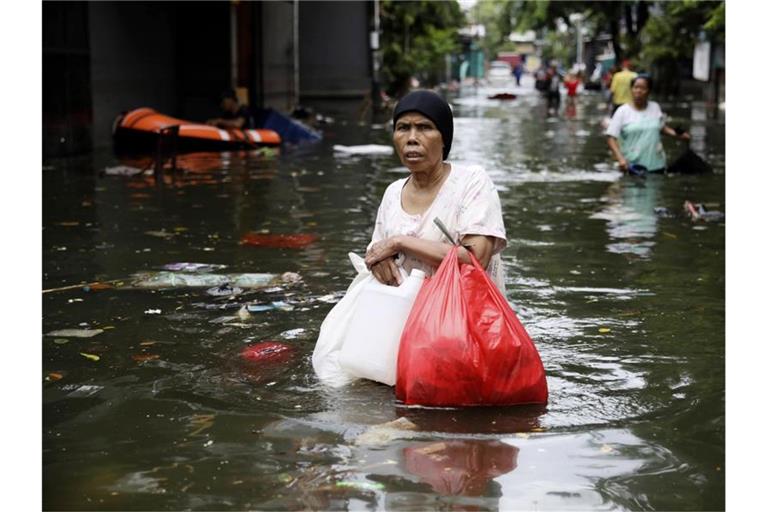 Eine Frau geht durch das Hochwasser einer überfluteten Straße in Jakarta. Foto: Dita Alangkara/AP/dpa