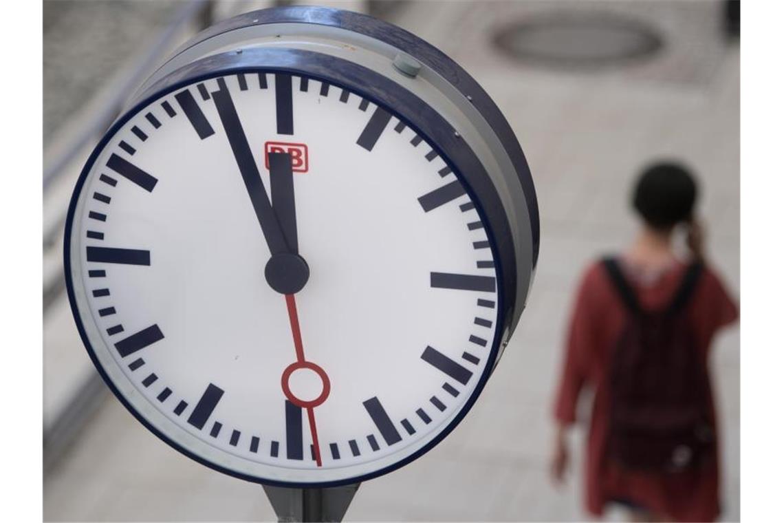 Stellwerksstörung: Verspätungen und Zugausfälle in Schwaben Eine Frau geht hinter einer Bahnhofsuhr auf einem Bahnsteig entlang. Foto: Sebastian Kahnert/Archivbild