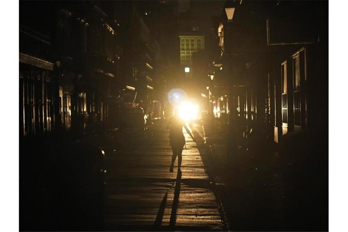 Eine Frau geht im Scheinwerferlicht eines patrouillierenden Polizeiwagens über die Bourbon Street in New Orleans. Foto: Eric Gay/AP/dpa