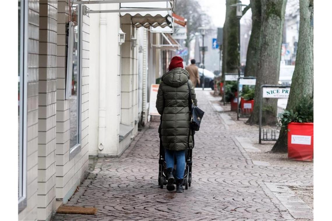 Eine Frau geht in Ahrensburg bei Hamburg durch eine leere Einkaufsstrasse. Foto: Markus Scholz/dpa