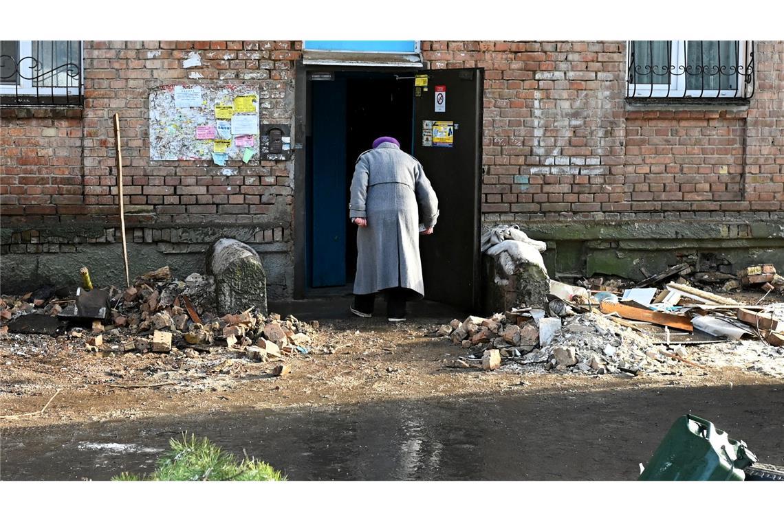 Eine Frau geht in ein beschädigtes Haus.