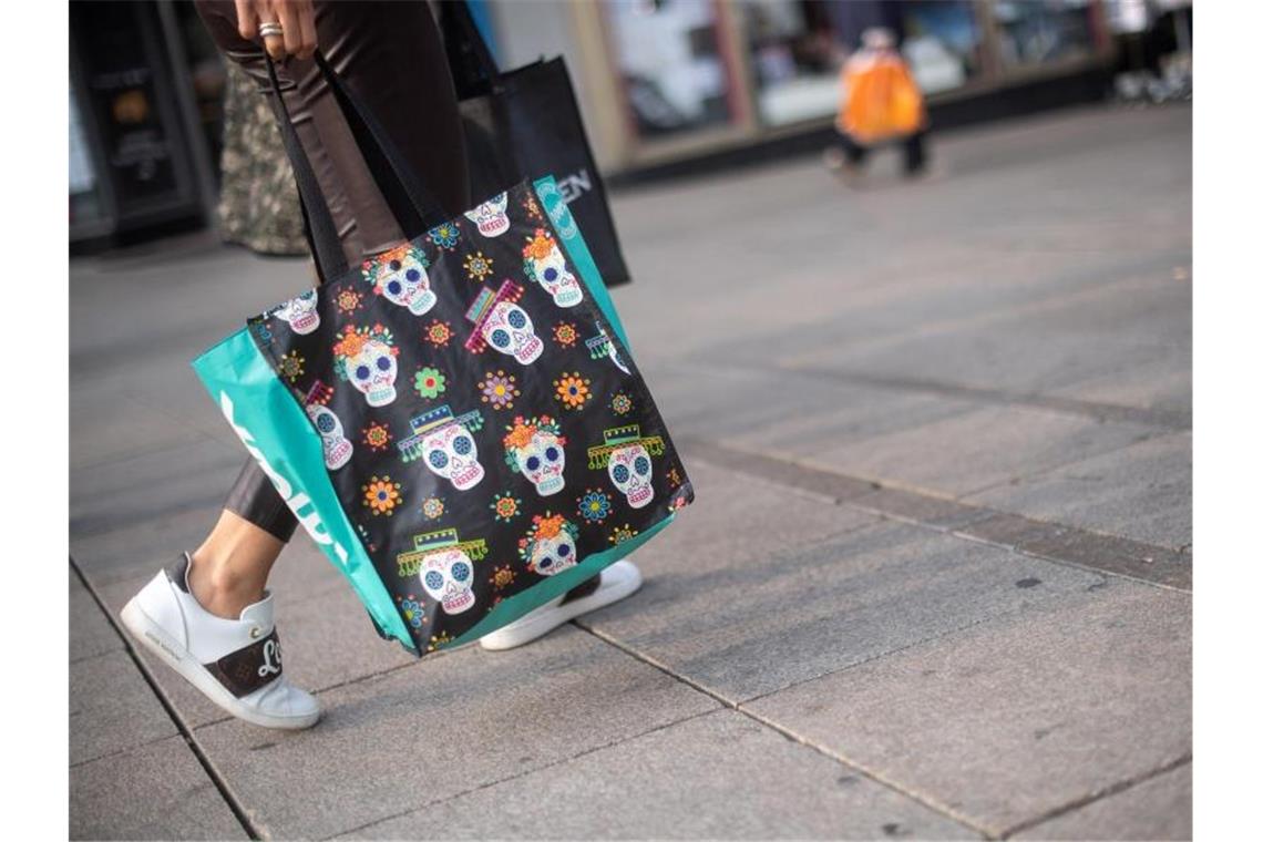 Eine Frau geht mir einer Einkaufstasche durch die Innenstadt. Foto: Sebastian Gollnow/dpa