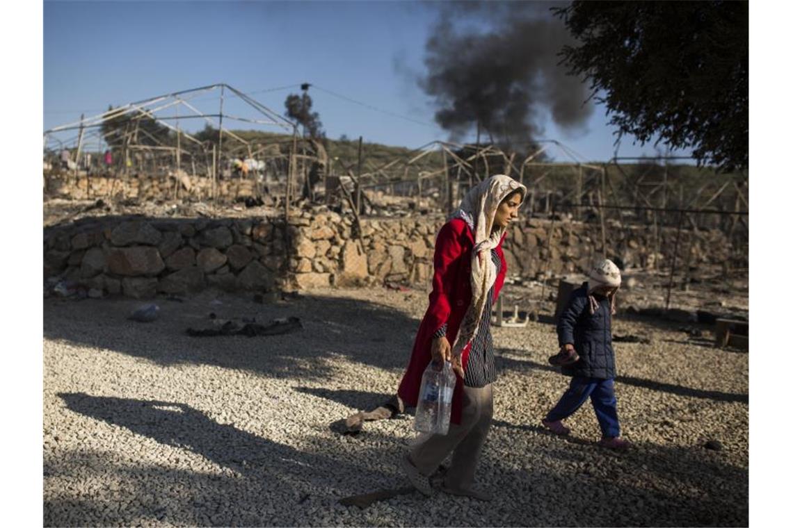 Eine Frau geht mit ihrem Kind durch das ausgebrannte Flüchtlingslager Moria. Foto: Socrates Baltagiannis/dpa