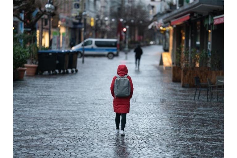 Eine Frau geht morgens durch die nahzu menschenleere Innenstadt. Foto: Frank Rumpenhorst/dpa/Archivbild