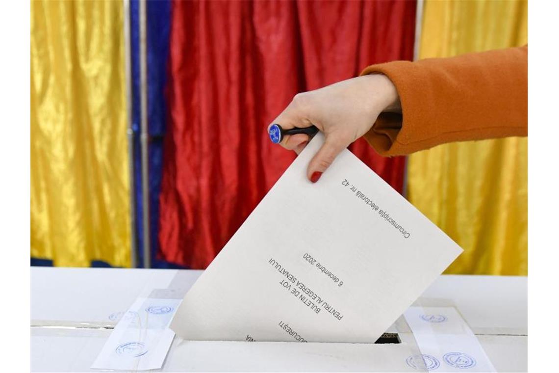 Eine Frau gibt ihren Stimmzettel ab. Die Wahlbeteiligung lag nach Angaben des Wahlbüros in Bukarest kurz vor Schließung der Wahlbüros bei 31,84 Prozent. Foto: Andreea Alexandru/AP/dpa