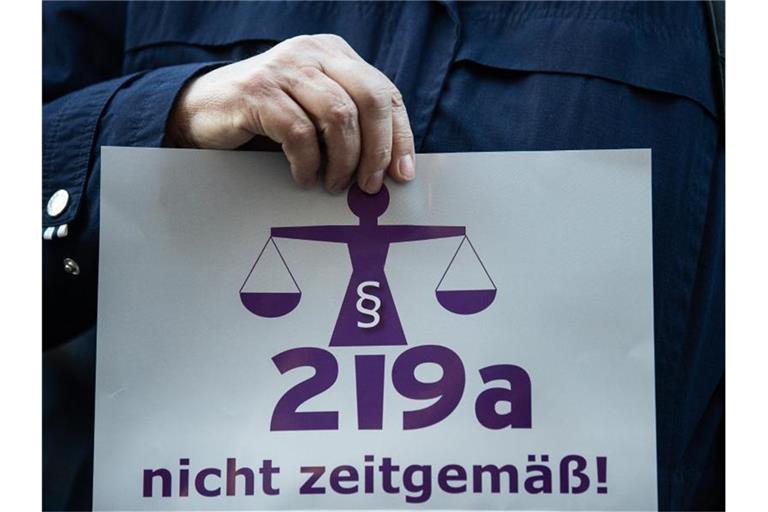 Eine Frau hält bei einer Kundgebung einen Zettel mit der Aufschrift „219a nicht zeitgemäß!“. Foto: Silas Stein/dpa