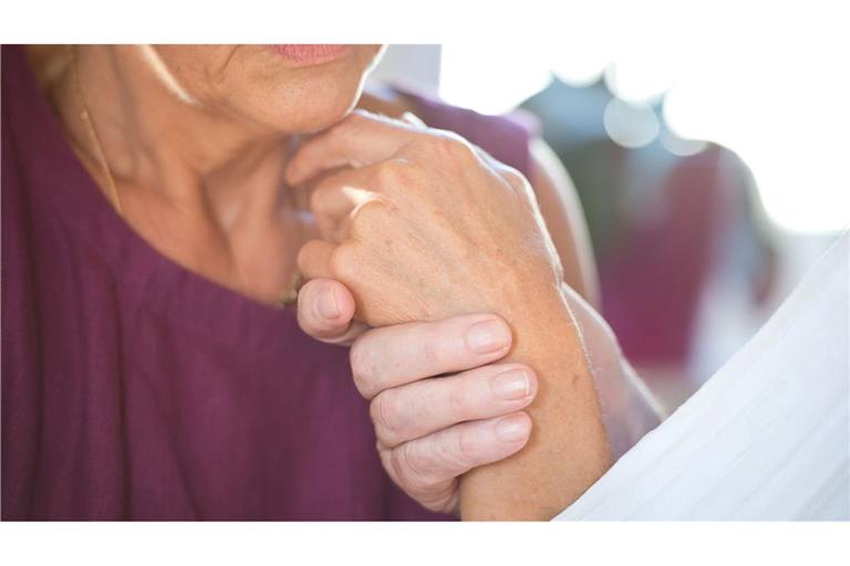 Eine Frau hält die Hand ihres an Demenz erkrankten Mannes.