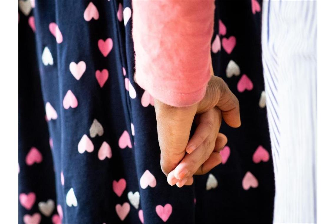 Eine Frau hält ein Mädchen an der Hand. Foto: Christian Charisius/dpa