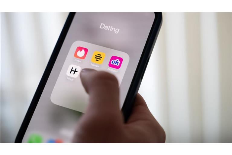 Eine Frau hält ein Smartphone, auf dem Dating-Apps angezeigt werden. (Symbolbild)