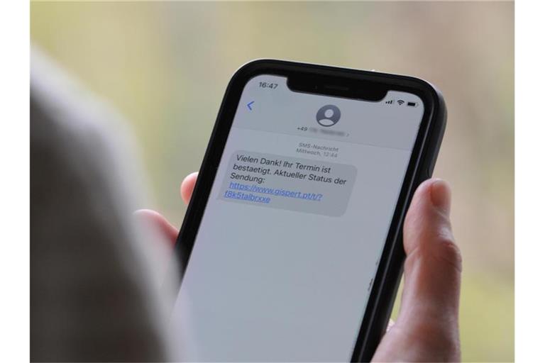 Eine Frau hält ein Smartphone in ihrer Hand, auf dessen Display eine Betrugs-SMS zu lesen ist. Foto: Wolf von Dewitz/dpa